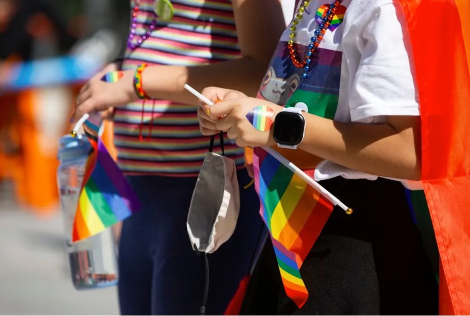 Kids hold flags and wear heart stickers and beads at the Austin Independent School District’s “Pride Out!” party in Austin last month. Lt. Gov. Dan Patrick wants a Texas law similar to Florida legislation limiting classroom lessons about LGBTQ people.